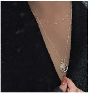 Detail of layered S925 silver necklaces with irregular round pendant on black sweater