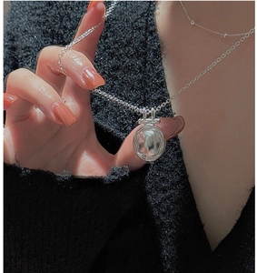 Close-up of a silver hammered disk pendant necklace worn on a black knit sweater