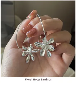 Close-up of S925 sterling silver flower hoop earrings held by hand in warm setting