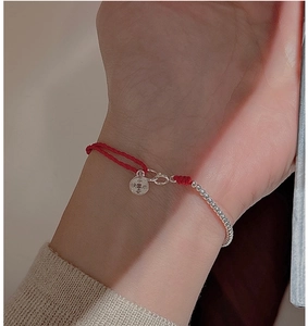 Close-up of red braided rope bracelet with S925 silver beads and engraved charm