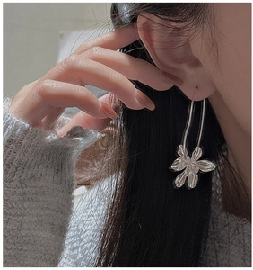 Close-up of a model wearing the silver flower dangle earring with long U-shaped hook