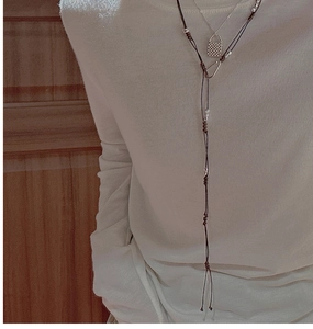 Détail du pendentif serrure en argent S925 et du collier pull multicouche en corde brune