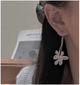 Detailed view of silver flower drop earrings worn by a model with a polished finish