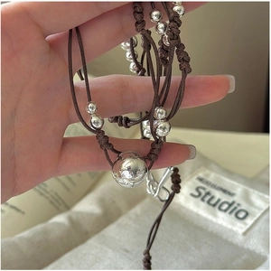Détails d'un collier en corde tressée marron avec perles en argent poli brillant