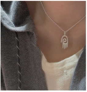 Vue macro du collier avec pendentif main en argent sterling S925 sur un vêtement en maille