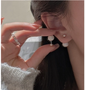 Close-up of elegant double pearl earrings and polished heart-shaped stackable ring