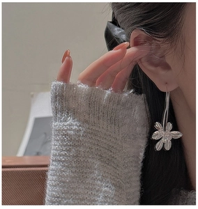 Detailed close-up of a large silver flower earring worn by a model in a side profile view