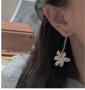 Close-up of a silver floral drop earring worn by a model in a retro setting