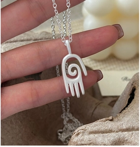 Vue macro d'un collier en argent S925 mat avec pendentif main en spirale et chaîne