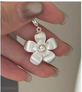 Macro detail of S925 silver flower pendant with brushed texture and central pearl