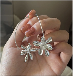 Macro detail of large silver flower hoop earrings held by hand in S925 sterling silver