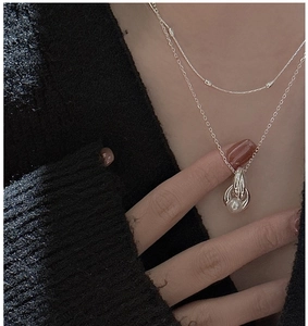 Detail of S925 sterling silver layered necklace with pearl pendant on a black knit sweater