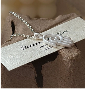 Détail du collier pendentif main en argent massif S925 mat sur une carte cadeau