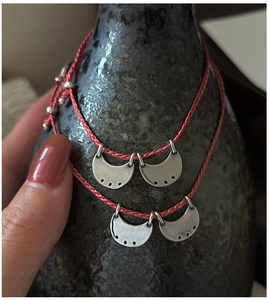 Detail of red woven bohemian bracelet with vintage silver crescent moon pendants