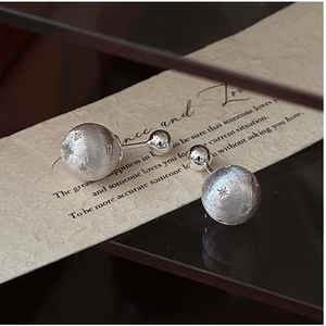 Detail of matte brushed silver star earrings on a text paper card with a soft shadow
