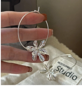 Macro shot of silver-plated large hoop earrings featuring a unique 3D liquid metal flower pendant