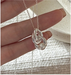 Close-up of S925 silver necklace featuring intertwined rings and a round white pearl