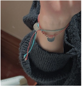 Close-up of woven rope bracelets with moon pendants in red and cyan colors