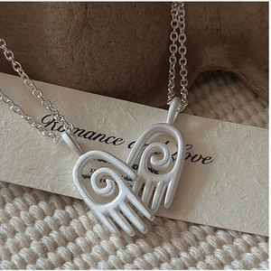 Vue macro du pendentif cœur mat en argent S925 avec texture en spirale de doigt