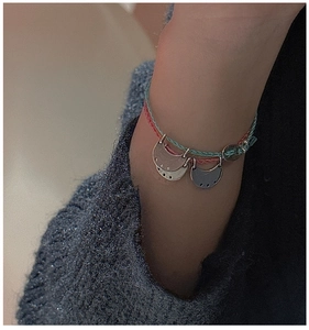 Detail of hand-woven cord bracelets featuring crescent moon charms on model's wrist