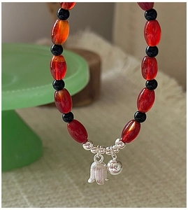 Detail of S925 silver tulip and bell charms on red agate beaded bracelet for women