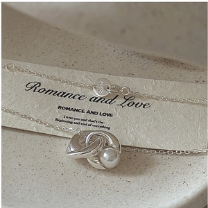 Macro detail of Ag 925 sterling silver twisted knot pendant with a lustrous white pearl