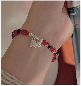 Detail of red agate and S925 silver beaded bracelet on wrist with flower charms