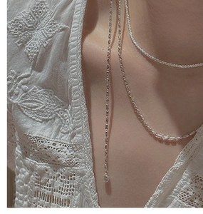 Macro shot of layered S925 silver necklaces with olive beads on elegant lace top