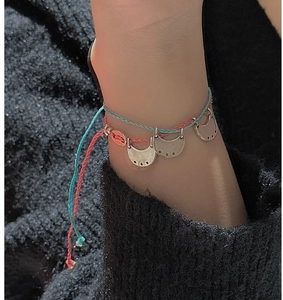 Detail of bohemian double-layered woven anklet with vintage metal crescent moon charm