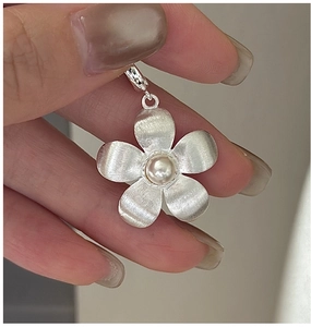Close-up of S925 silver flower pendant featuring brushed texture and a white pearl accent