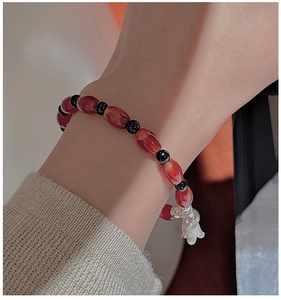Close-up of red agate beaded bracelet with silver calla lily charm on wearer's wrist