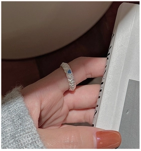 Close-up of retro S925 silver ring with blue heart zircon on a finger
