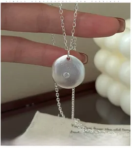 Close-up of S925 silver round pendant with brushed texture and sparkling zircon stone