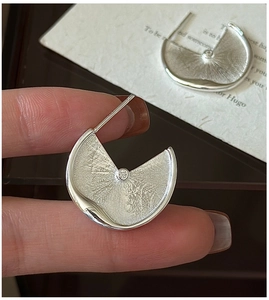 Macro detail of S925 sterling silver fan-shaped earring with brushed texture and small zircon