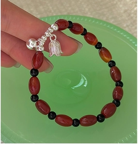 Detail of vintage silver beaded bracelet featuring red agate and tulip floral charm