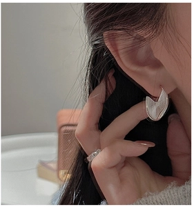 Close-up of S925 sterling silver earrings with textured circular disc design on ear