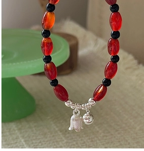 Detail of S925 silver calla lily bracelet with red agate beads and a small silver bell