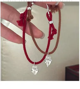 Close-up of woven rope bracelets with silver heart lock and key charms for couples