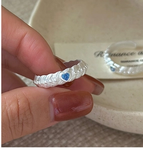 Macro detail of silver lava texture ring with a blue heart zircon and adjustable band
