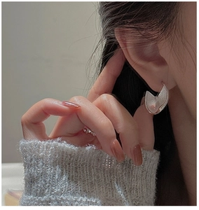 Detailed view of silver S925 textured earrings with a modern irregular crescent design
