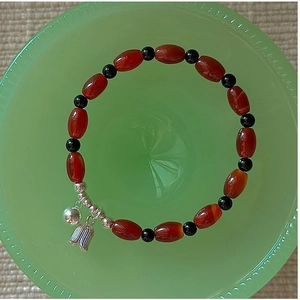 Close-up of vintage S925 silver tulip charm and red agate beads on a beaded bracelet