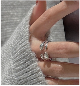Detailed view of a silver minimalist crossover ring worn on a model's hand