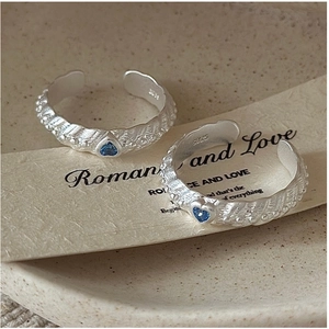 Detailed macro view of S925 sterling silver rings with blue heart-shaped zircons and texture