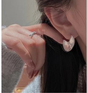 Close-up of S925 sterling silver earrings and textured ring with brushed metal finish