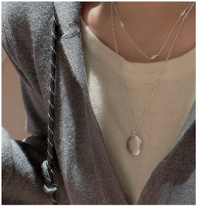 Close-up of layered S925 silver necklace with diamond rhombuses and round pendant on model