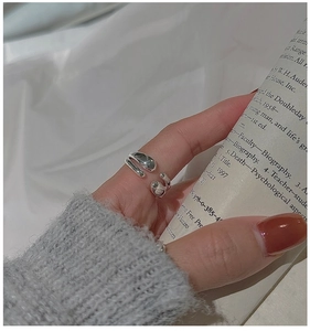 Detail of silver crossover ring featuring a sleek water drop design on female finger
