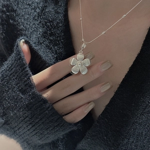 S925 sterling silver flower necklace with brushed texture and pearl center on black knitwear