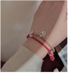Close-up of red and brown braided rope bracelets with silver heart lock and key charms