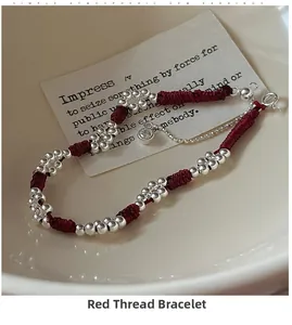 Detail of red woven bracelet with silver beads and sparkling zircon charm on card