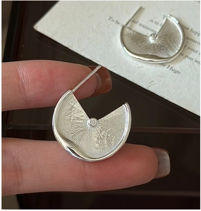 Detail of S925 silver fan-shaped earrings with brushed texture and center zircon